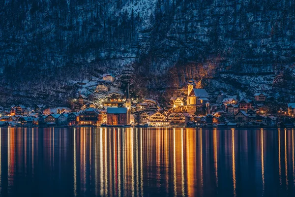 Beautiful Austrian village Hallstatt by lake covered with snow in winter at dusk time — Stock Photo, Image