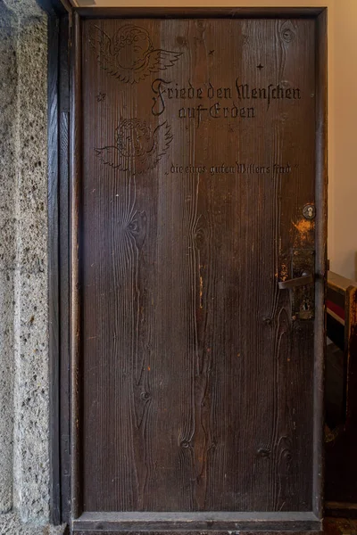 Feb 3, 2020 - Oberndorf, Austria: Ángel grabado y nombre en la puerta roja de la capilla de Stille-Nacht-Kapelle — Foto de Stock
