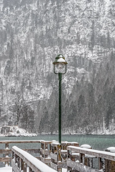 Streetlight by Konigssee lake dock during heavy snow in winter time