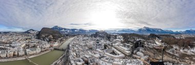 Hava aracı kışın nehir ve dağ sırtları boyunca karlı Salzburg şehrini görüntüledi.