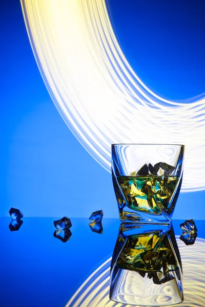 칵테일 위스키 파티 개념 파란색 배경에서 조명 효과의 조각 얼음 유리. — 스톡 사진
