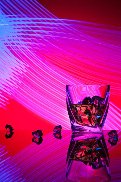 Koktajl whisky z kawałków lodu szklankę strony koncepcja fioletowy efekty świetlne na czerwonym tle. — Zdjęcie stockowe