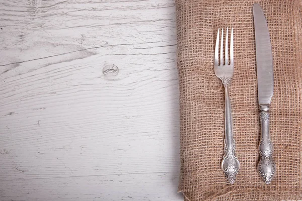 Vintage silver tableware knife and  fork is on napkin, on an old table.
