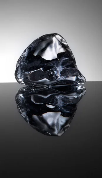 Один прохладный кристалл льда с водой на зеркальном фоне — стоковое фото