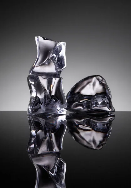 Три кубика льда кристаллический объект с водой на фоне зеркала — стоковое фото