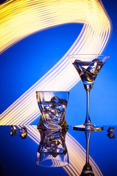 두 아름 다운 조명 효과의 파란색 배경에 대해 칵테일 마티니 위스키 얼음 안경. — 스톡 사진