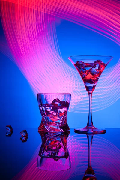 Två glasögon en cocktail Martini whisky is, mot blå bakgrund av vackra ljuseffekter. — Stockfoto