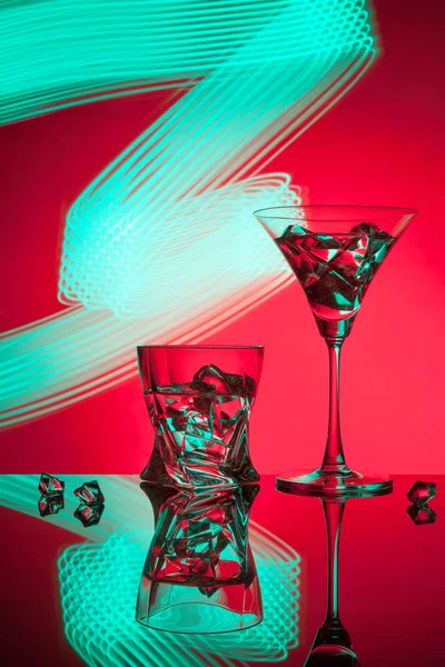 두 아름 다운 조명 효과의 빨간 배경에 대해 칵테일 마티니 위스키 얼음 안경. — 스톡 사진