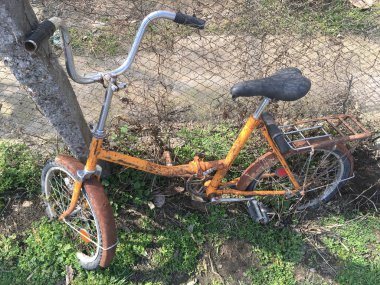 Yalnız eski bisiklet ile bir ot, turuncu bir çerçevede paslanacak