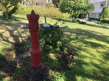 Otel bahçesinde yangın ihtimaline karşı güvenlik ve su için klasik kırmızı itfaiye musluğu..