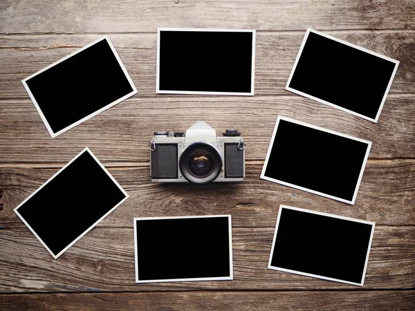 Cámara vintage sobre fondo de madera con marcos de fotos en blanco — Foto de Stock