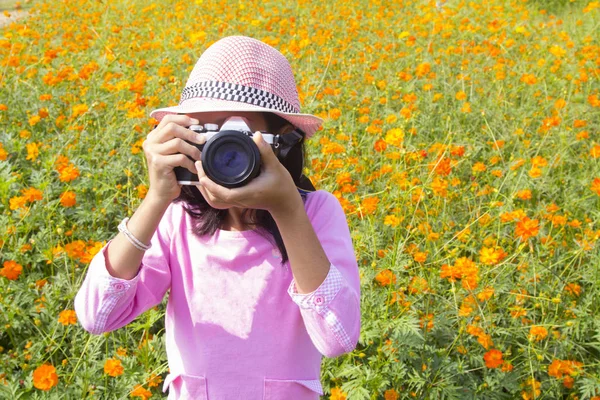 Дівчина тримає камеру в саду квітів — стокове фото