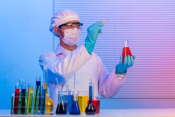 Hombre científico sosteniendo un tubo de ensayo con líquido, Con pluma de retención —  Fotos de Stock