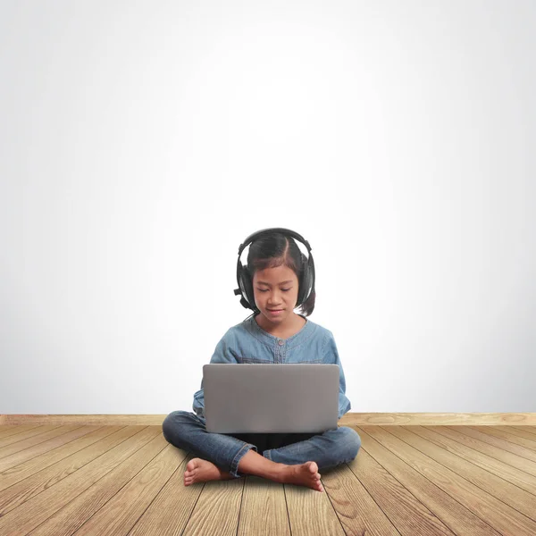 Gadis kecil duduk di lantai dengan menggunakan komputer laptop — Stok Foto