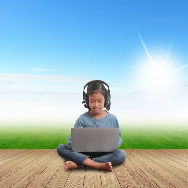 Gadis dengan laptop duduk di rumput hijau langit biru — Stok Foto