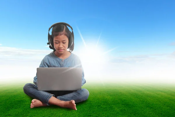 Gadis dengan laptop duduk di rumput hijau langit biru — Stok Foto