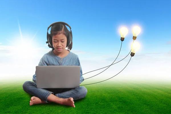 Gadis kecil menggunakan laptop dengan ide bola lampu kreatif. — Stok Foto