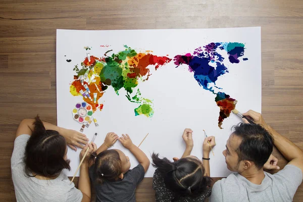 Top view happy family lying on floor with painting watercolor world map — Stock Photo, Image