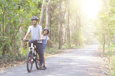 Mutlu baba ve kız parkta Bisiklete binme