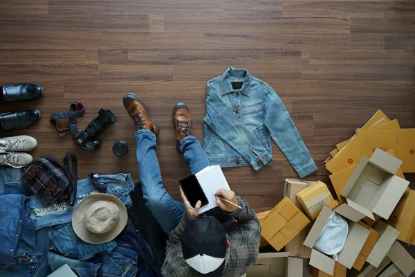 Ovanifrån om man skriver en anteckningsbok med holding smart telefon och jean jecket — Stockfoto