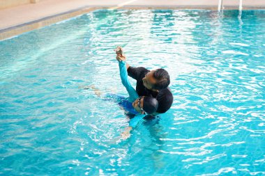 Bir yüzme havuzunda yüzmeyi baba öğretim kız