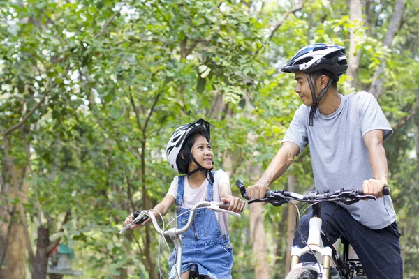 Happy father and daughter cycling in the park