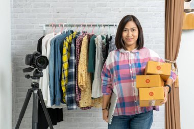 Asyalı kadınlar ellerinde dizüstü bilgisayarla kahverengi paket ya da karton kutular taşıyorlar, internette satıyorlar. 
