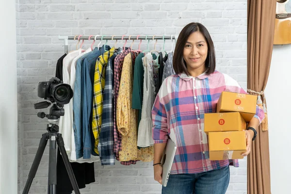 Asiatische Frauen, die einen Laptop mit braunen Paketen oder Pappschachteln in der Hand halten und online verkaufen — Stockfoto