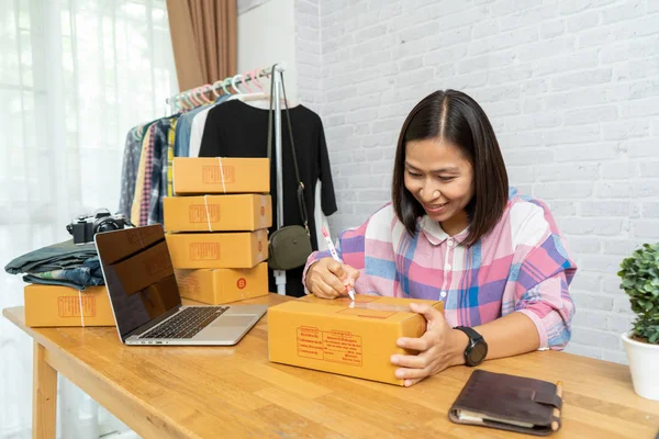 Asian women selling online start up small business owner working, With write address on the postal parcel at home office