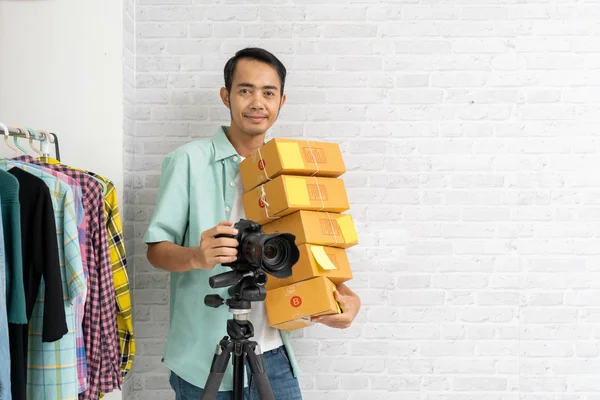 Азіатський чоловік тримає фотоапарат з коричневою посилкою. — стокове фото
