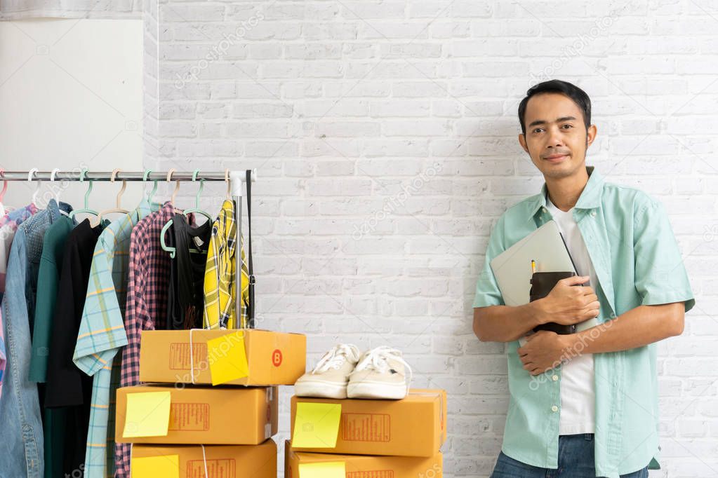 Asian man standing holding laptop computer selling online start 