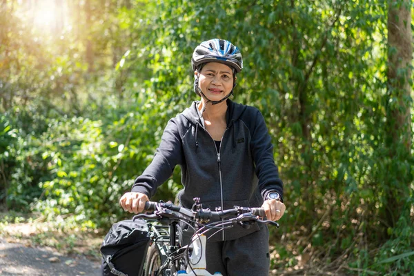 Atraente sênior asiático mulher com bicicleta no parque — Fotografia de Stock
