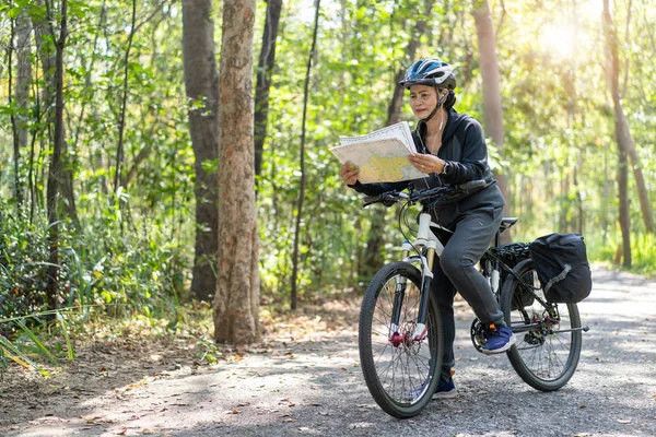 Senior asiatico donna equitazione biciclette in parco con hold e guarda mappa o — Foto Stock