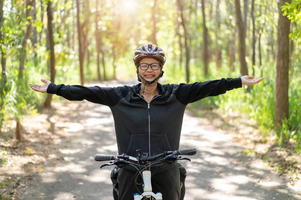Sênior asiático mulher andar de bicicleta no parque — Fotografia de Stock