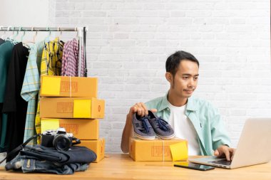 İç işlerinde çalışan Asyalı bir adam, internette satış yapıyor, küçük işletme sahibi e-ticaret kuruyor.