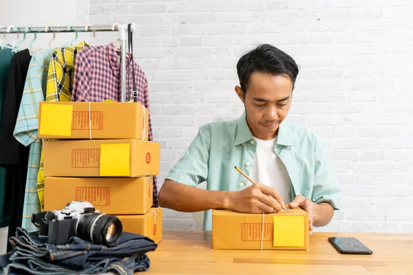 茶色の小包や段ボール箱を運ぶ自宅のオフィスで働くアジア人男性 電子商取引のアイデアのコンセプト — ストック写真