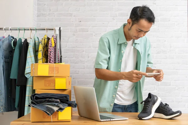 インターネット上でオンラインで販売するポストのためのスマートフォンで靴に写真を撮るアジアの男 自宅のオフィスで小さなビジネスの所有者の仕事を開始 — ストック写真