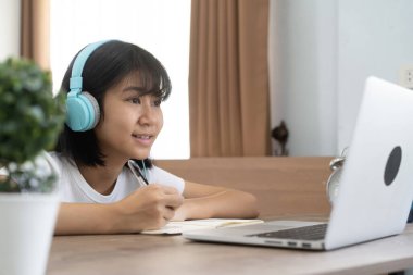 Asyalı kız internette ödev okuyor evde ders veriyor, sosyal uzaklık online eğitim fikri