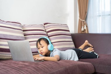 Asyalı küçük kız evde ev ödevi okuyor, sosyal uzaklık online eğitim fikri.