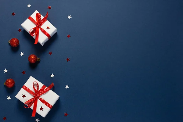 Christmas banner with gift white boxes, decorative red shiny balls and stars on a classic blue background. New year.