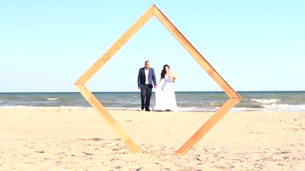 Coppia appena sposata a piedi lungo la riva del mare — Video Stock