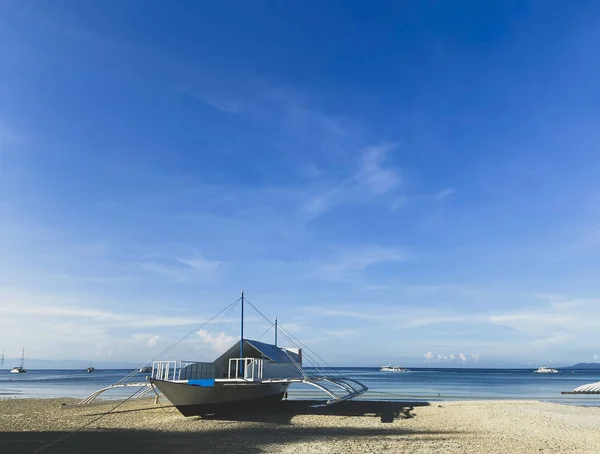 Mavi sakin deniz ve bulutlu gökyüzünün arka planında güzel beyaz bir gemi. Tekneler ufukta. Sıcak kumsalda.