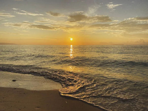 İnanılmaz güzel, muhteşem bir gün batımı, kumlu bir sahilde gün doğumu. Bulutlar ve mavi-turuncu gökyüzü üzerinde sakin bir deniz.