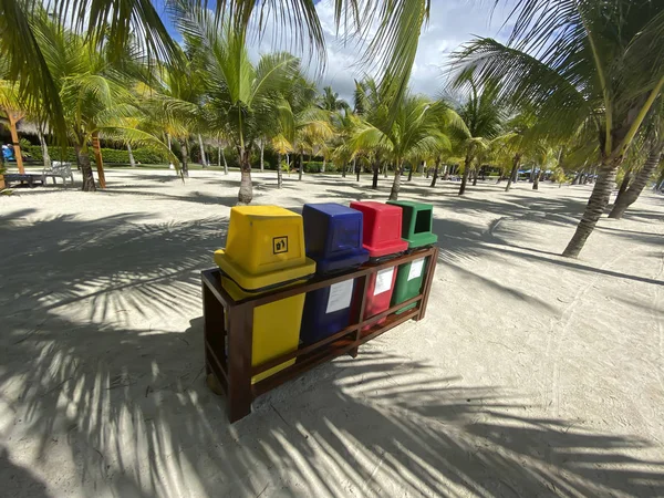 Contenitori colorati per la raccolta dei rifiuti su una spiaggia di sabbia bianca in una foresta di palme. Ecologia, riciclo . — Foto Stock