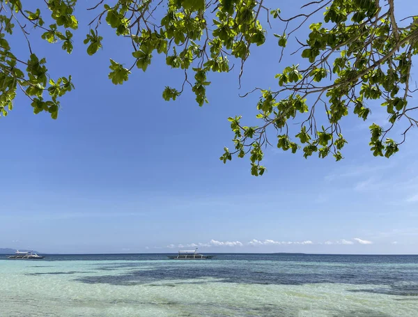 Temiz turkuaz suyla inanılmaz güzel bir kıyı manzarası. Ufuktaki tekneler bulutlu mavi gökyüzüne doğru sürüklenir..