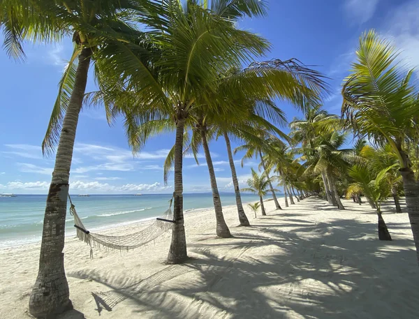 Amaca rilassante in una foresta di palme.Bellissimo paesaggio su una spiaggia di sabbia bianca. Barche sullo sfondo del mare turchese e il cielo blu con le nuvole . — Foto Stock