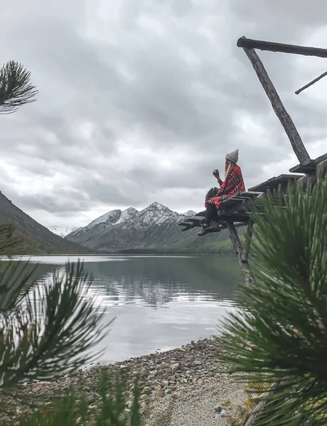 Sarışın kız kareli kırmızı ekose içinde yan yana oturur. Güzel göl, orman, dağlar.