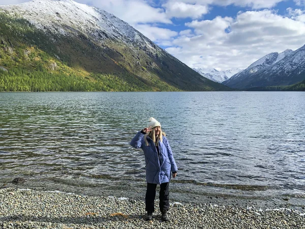 Güzel sarışın kız gülümsüyor arka planda kar dağları, göl manzarası