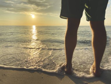 Şortlu adam gün batımıyla tanışır. Köpüklü deniz dalgası bacaklara dokunur. Huzur.