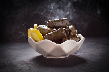 Lokanta tabağında servis edilen sarmaşık yaprakları, siyah arka planda...